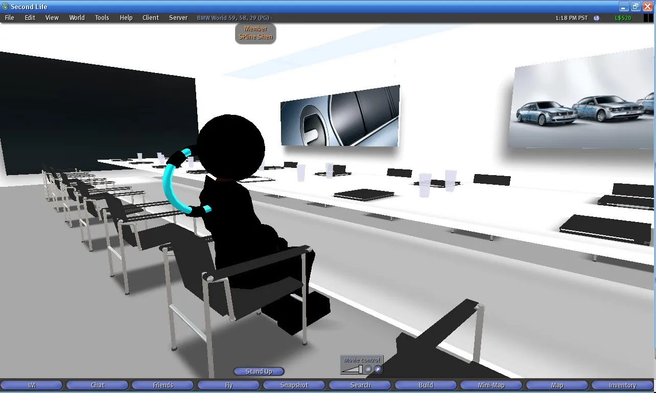 Second-Life-Präsentationsraum mit Sitzreihen und einer schwarzen Avatar-Silhouette an einem Tisch, an der Wand eine Nahaufnahme einer dunklen Fahrzeugkarosserie und ein Foto mit drei BMW-Fahrzeugen, oben in der Kopfzeile die Uhrzeit 1:18 PM PST und das Guthaben L$520